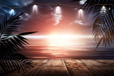 İskelede bir gece feneri, gün batımlı bir deniz manzarasının arka planına karşı. Palmiye dalları, siluetler, güneş ışığı. Tahta masa. Gece görüşü, açık deniz manzarası.