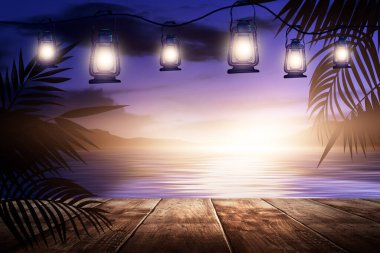 İskelede bir gece feneri, gün batımlı bir deniz manzarasının arka planına karşı. Palmiye dalları, siluetler, güneş ışığı. Tahta masa. Gece görüşü, açık deniz manzarası.