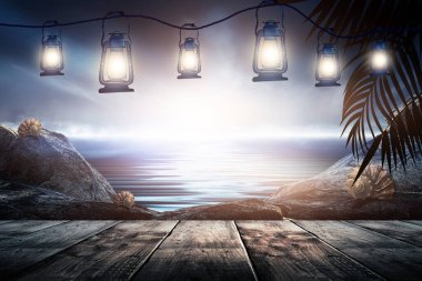 İskelede bir gece feneri, gün batımlı bir deniz manzarasının arka planına karşı. Palmiye dalları, siluetler, güneş ışığı. Tahta masa. Gece görüşü, açık deniz manzarası.