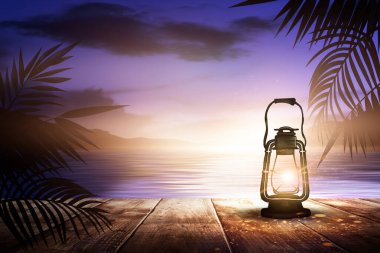 İskelede bir gece feneri, gün batımlı bir deniz manzarasının arka planına karşı. Palmiye dalları, siluetler, güneş ışığı. Tahta masa. Gece görüşü, açık deniz manzarası.