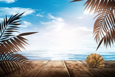 Gün batımlı deniz manzarası. Palmiye dalları, siluetler, güneş ışığı. Deniz kenarındaki tahta masa. Gece görüşü, açık deniz manzarası.