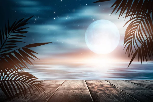 Gün batımlı deniz manzarası. Palmiye dalları, siluetler, güneş ışığı. Deniz kenarındaki tahta masa. Gece görüşü, açık deniz manzarası.