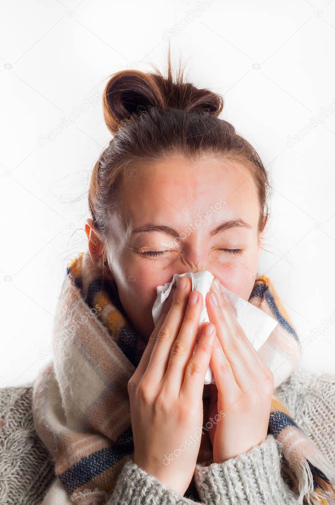 Girl with cold sneezing in handkerchief wearing scarf and sweate