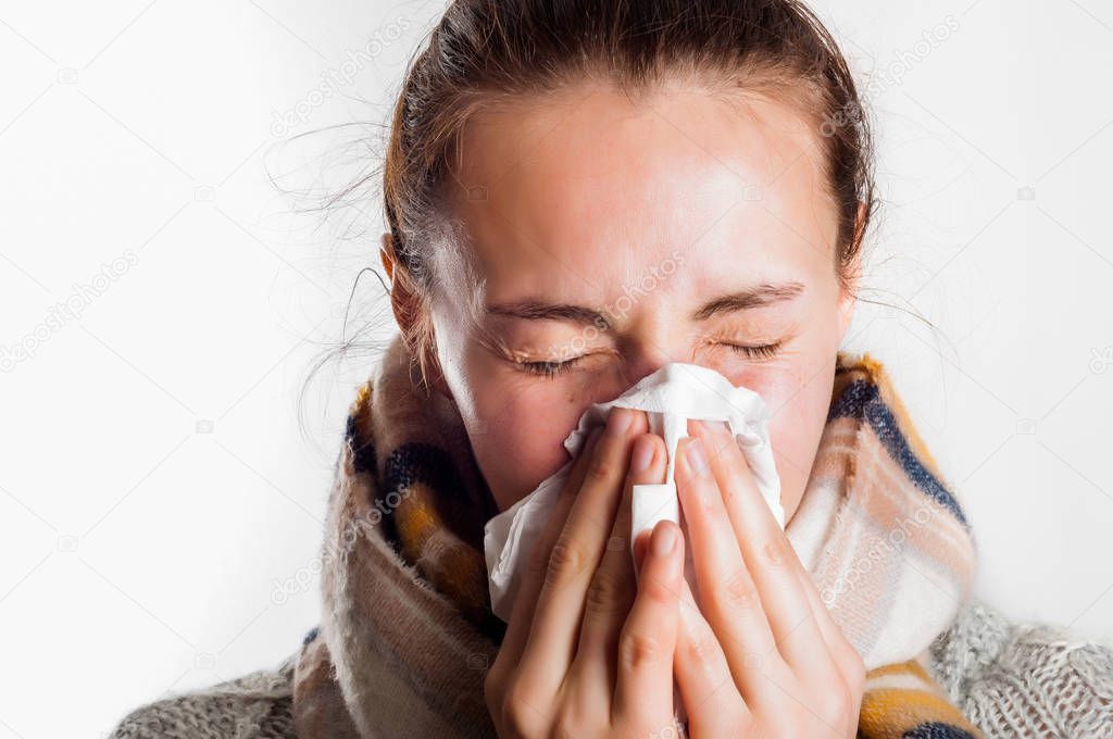Girl with cold sneezing in handkerchief wearing scarf and sweate