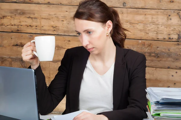 Femme d'affaires assise à son bureau et travaillant sur un ordinateur portable tenant — Photo
