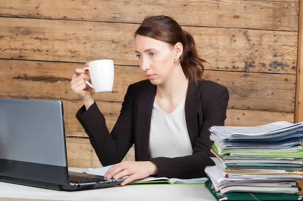 Femme d'affaires assise à son bureau et travaillant sur un ordinateur portable tenant — Photo