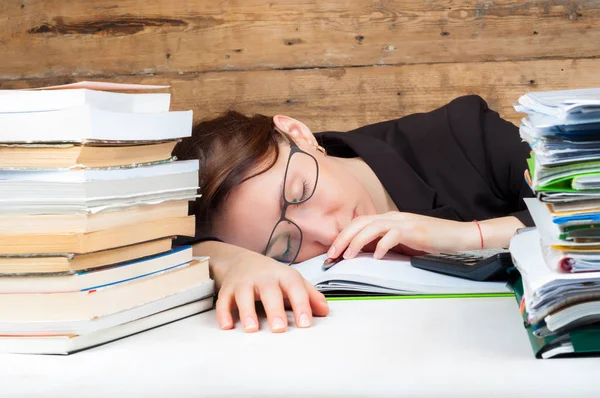 Жінка втомилася працювати і вчитися біля стопки паперу — стокове фото