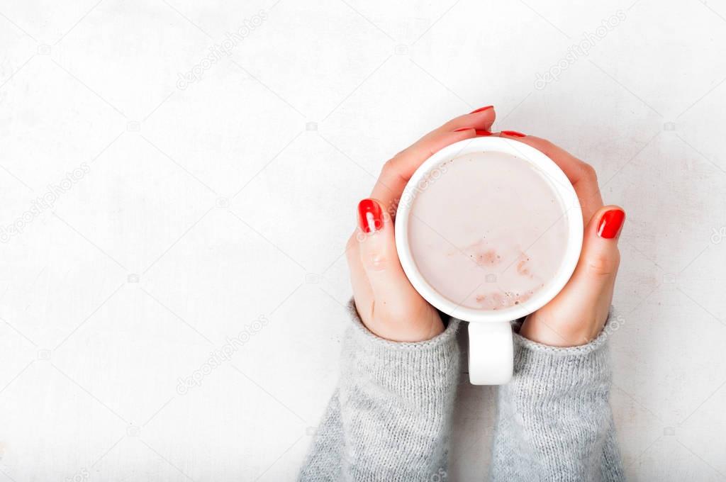 Woman with red fingernaild holding cup of hot cacao beverage on 
