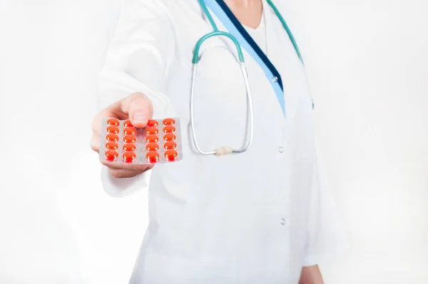 Женщина-врач держит в руках пачку красных таблеток, фокусируется на таблетках — стоковое фото
