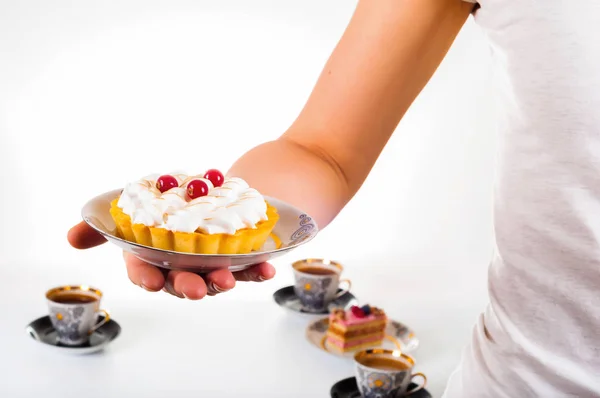 La mano de la mujer sosteniendo un pequeño pastel en un hermoso plato — Foto de Stock