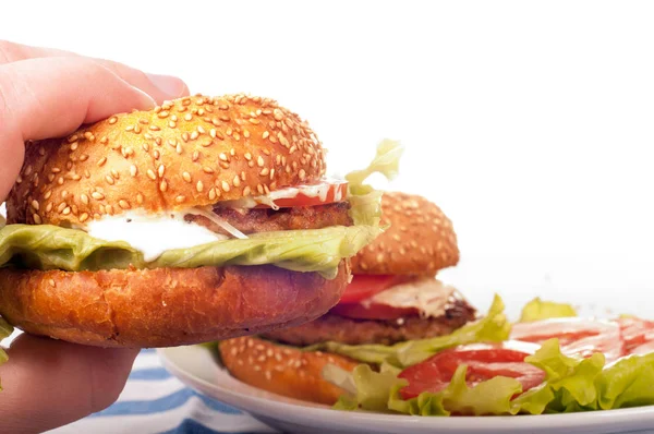 Рука держит свежий гамбургер. Изолированный на белом фоне — стоковое фото