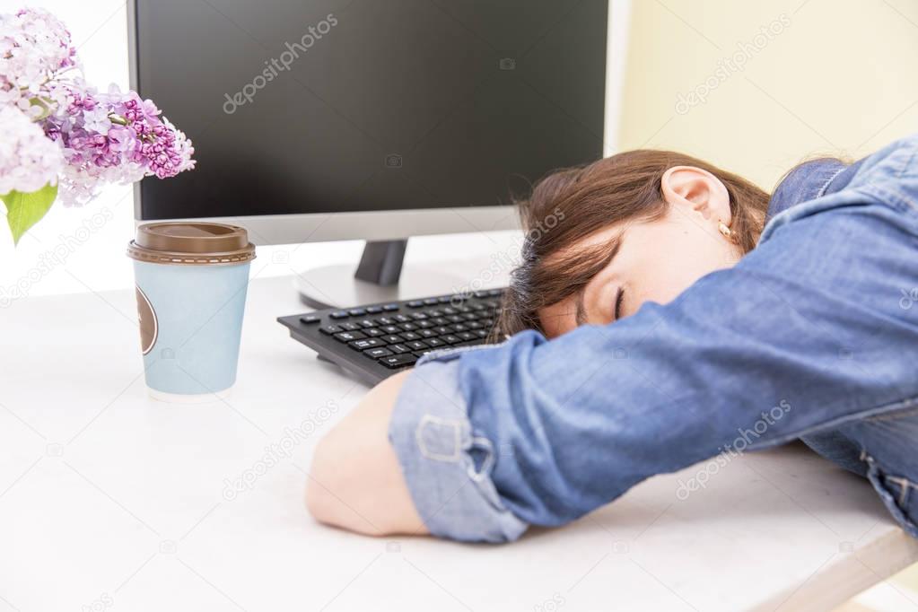 Young pretty woman tired and exhausted of work lying on table in