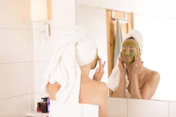 The woman applies green organic face mask in the bathroom — Stock Photo, Image