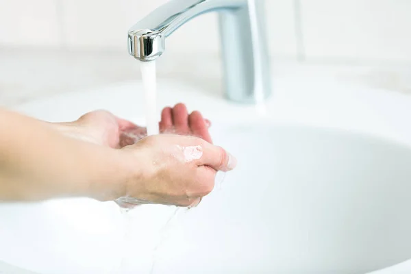 Una mujer lavándose las manos bajo el agua corriente de la grúa — Foto de Stock