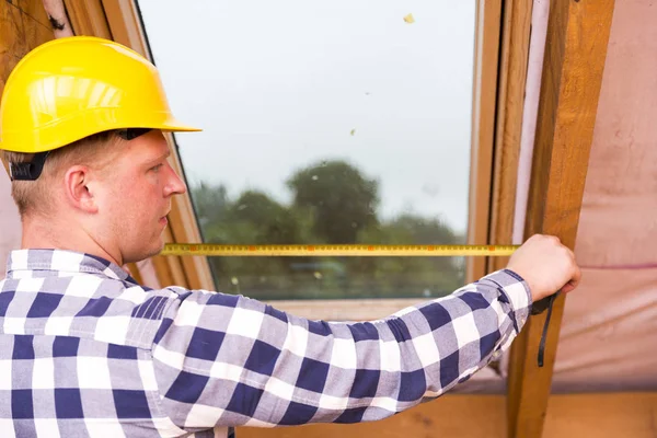 Разнорабочий в защитном шлеме, измерение окна на крыше, ремонт чердака — стоковое фото