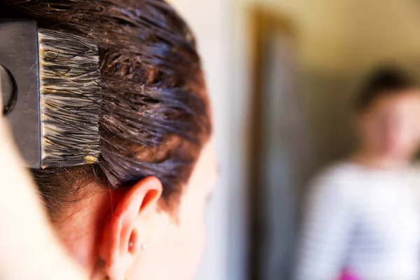 Woman with dying her hair in front of mirror in her own bathroom — Stock Photo, Image