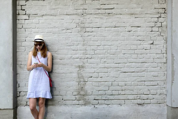 Şehir hayat kavramı. Yanındaki beyaz tuğla duran genç kadın 