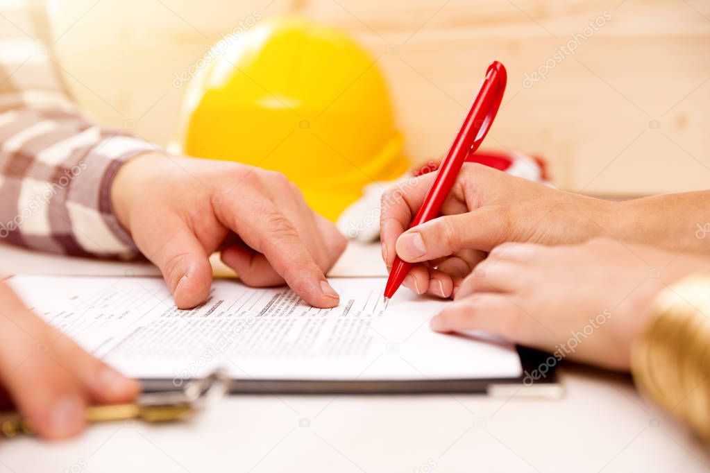 Woman signing construction contract with contractor to build a h