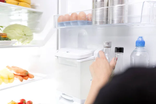Woman taking a glass bottle out of the fridge — Stock Photo, Image