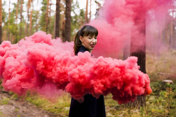 Jonge vrouw in het bos met plezier met rode rook granaat, bom — Stockfoto