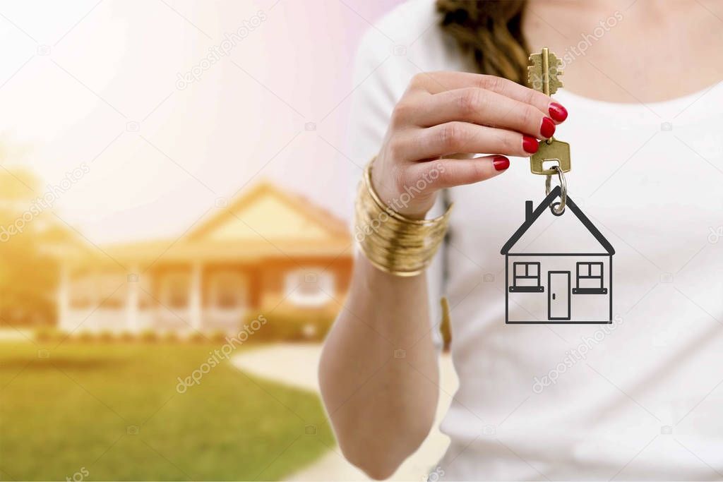 Real estate agent holding keys in front of a beautiful new home.