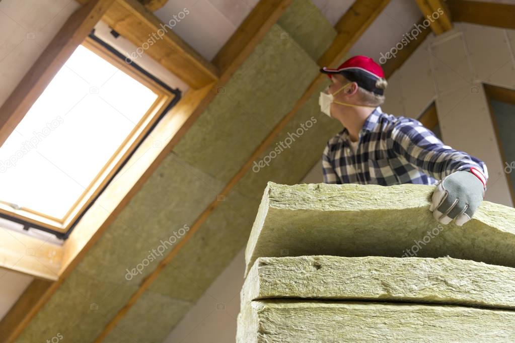 Man installing thermal roof insulation layer - using mineral woo