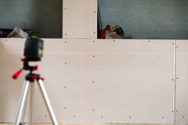 laser leveler in attic marking level on dry wall clipart