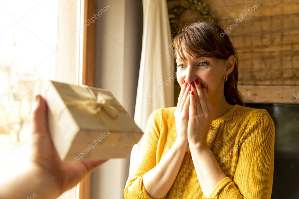 happy woman receiving a gift from husband by a window