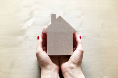 Prot bir işareti olarak elleri küçük beyaz model evde tutan kadın