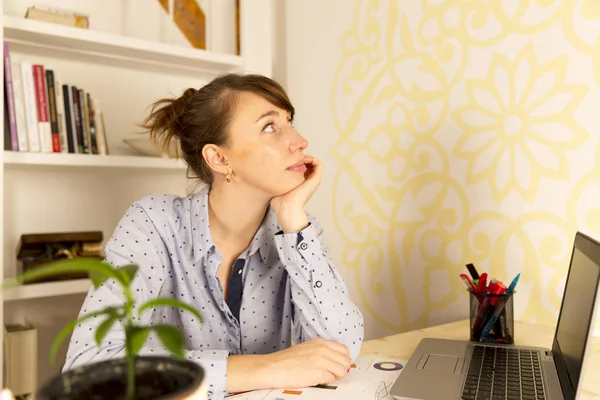 Mladá žena pracuje na její laptop doma při pohledu na stranu v t — Stock fotografie