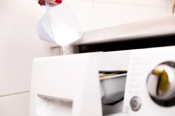 Женщина наливает стиральный порошок в стиральную машину — стоковое фото