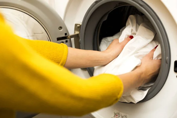 Женщина вручную загружает грязную одежду в стиральную машину — стоковое фото