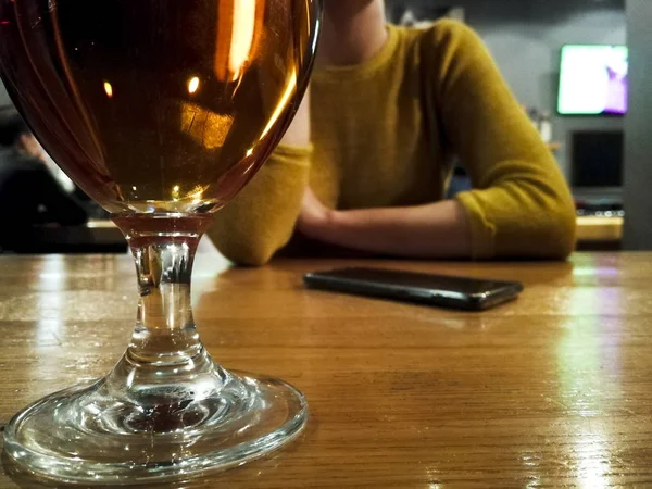 Žena sedí u baru, sklenice piva v z v zaměření — Stock fotografie
