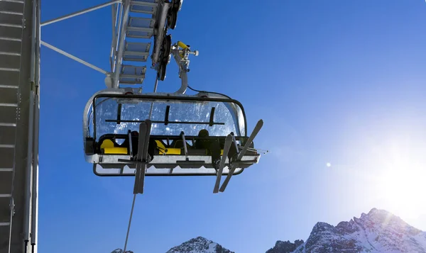 Skiërs omhoog op de stoeltjeslift tegen heldere blauwe hemel-ski-oord in Italië op zonnige winterdag — Stockfoto