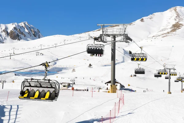 Dzieje się na wyciągu krzesełkowego przeciw jasne niebo niebieski-ski resort w Włochy na dzień słoneczny zimowy narciarzy — Zdjęcie stockowe