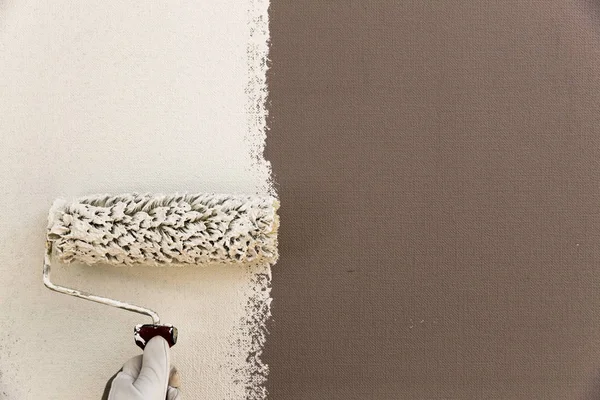 Mão do decorador pintura parede branca com rolo — Fotografia de Stock