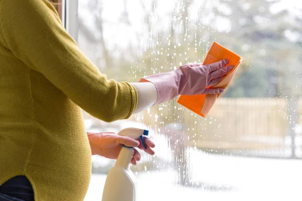 Donna incinta pulizia finestra con panno e spray finestra. Gira — Foto Stock
