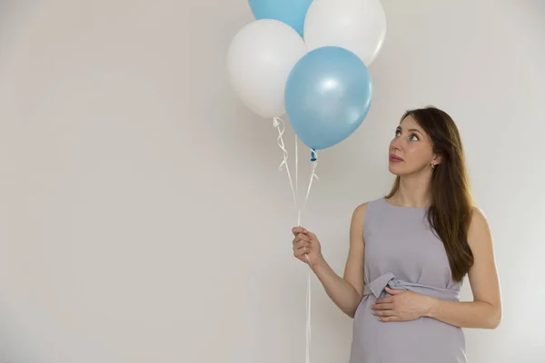 Gender reveal party. Pregnant woman holding blue and white ballo