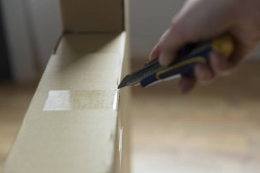 Yeni mobilyaların kutusunu bıçakla açan kadın.