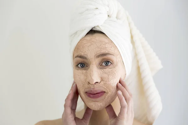 Atraktivní mladá žena s jílová maska obličeje. Lázeňská léčba — Stock fotografie