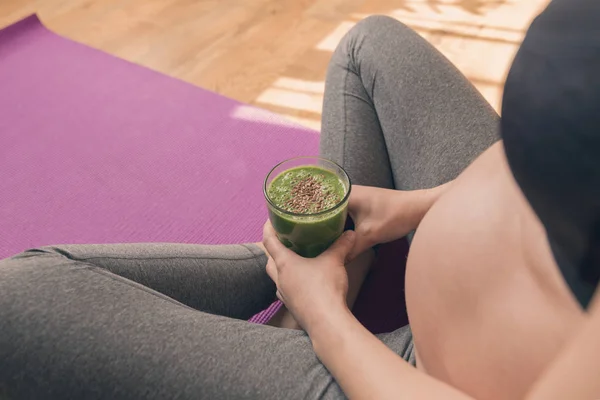 Schwangere trinkt gesunden grünen Smoothie im Sitzen — Stockfoto