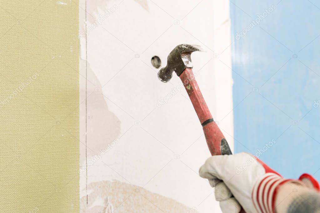 Builder hitting a wall with a hammer. Home renovation concept. Break wall to make new