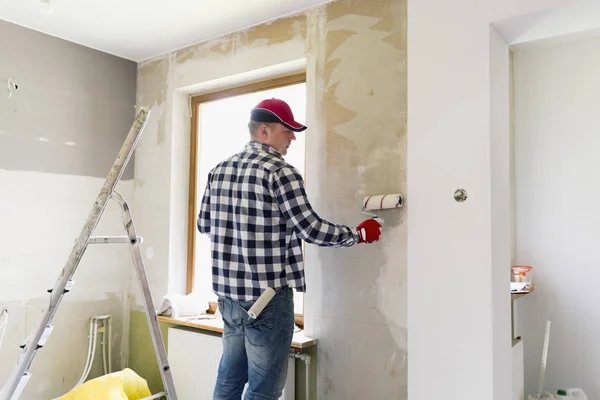 Glueing wallpapers at home. Young man, worker is putting up wall — Stock Photo, Image