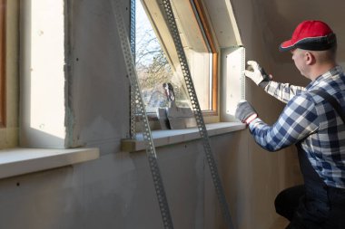 ev geliştirme ustası yeni inşa edilen tavan arasına pencere kuruyor