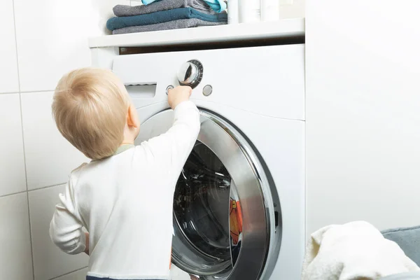 Двухлетний ребенок занимается домашними делами. Загрузка стиральных мачи — стоковое фото