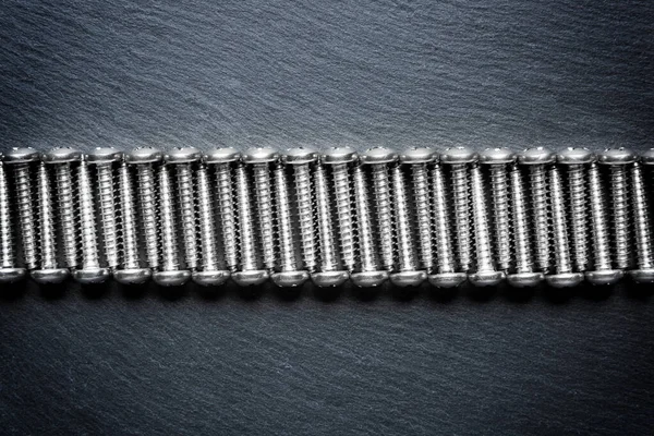 Stainless steel wood screws on a black texture background