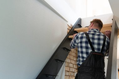 Ev dekorasyonu ustası merdivenleri doğal ışık altında inşa ediyor.