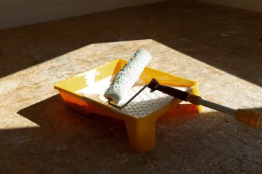 Ev tadilatı. Boyama aletleri silindir, boya kovası ve boya fırçası doğal ışık altında..