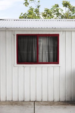 Beyaz renkli barakada küçük kırmızı pencere