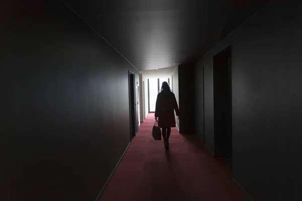 Chica caminando por oscuro pasillo en silueta — Foto de Stock